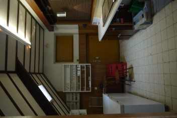 Een bar met een toog, drank-frigo's en een afwasbak. Een kast met glazen.